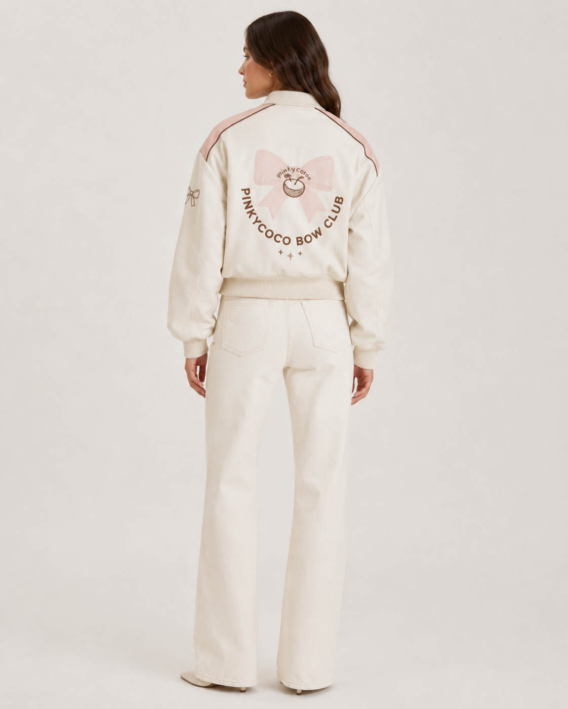 Model wearing PinkyCoco Coco Bow Ivory Women's Satin Bomber Jacket, three-quarter view